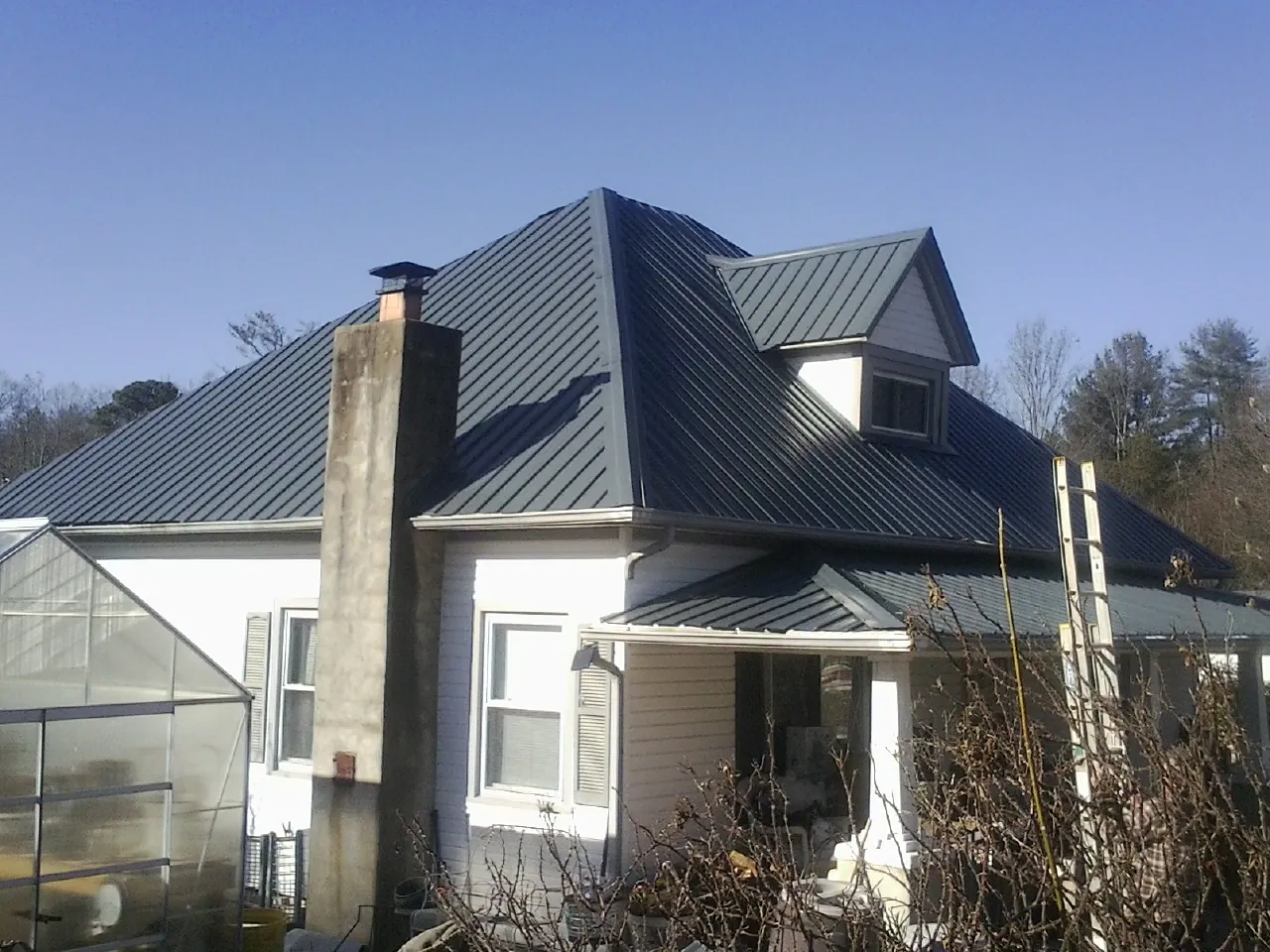 Dark blue standing seam metal roof on a white farmhouse with dormer — Slate & Tile Roof Repair by Roofing Brothers in Chaplin