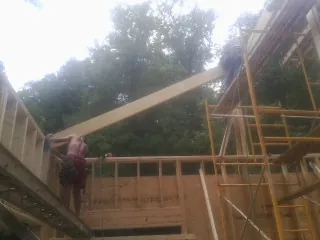 Carpenter raising a rafter beam on a new second story frame in Chaplin