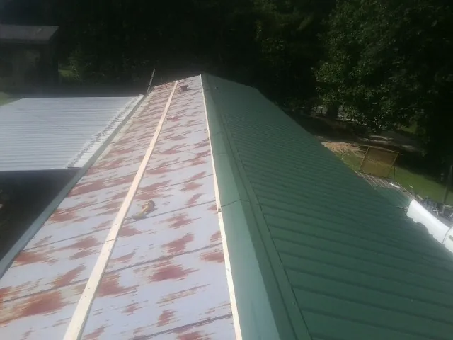 Old rusted panels beside newly installed green metal roofing — Wind Damage Roof Repair by Roofing Brothers in Chaplin