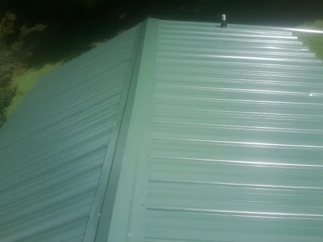 New green metal panels meeting at the ridge of a roof — Flat Roof Repair work by our crew in Chaplin