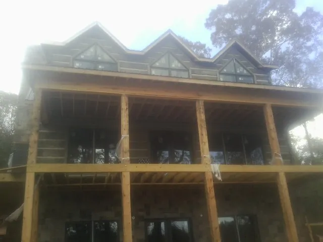 Dormers and porch framing on a large log home under construction — Roof Coating work by our crew in Chaplin