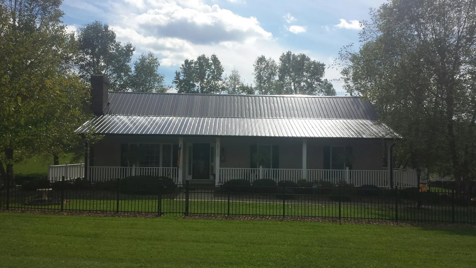 Gray metal roof on a brick ranch with a full width front porch — Gutter Guard Installation work by our crew in Chaplin
